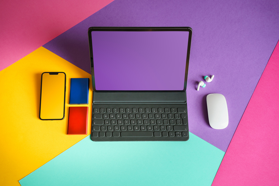 A laptop, phone and mouse on a colourful desk with the letters GED on screen